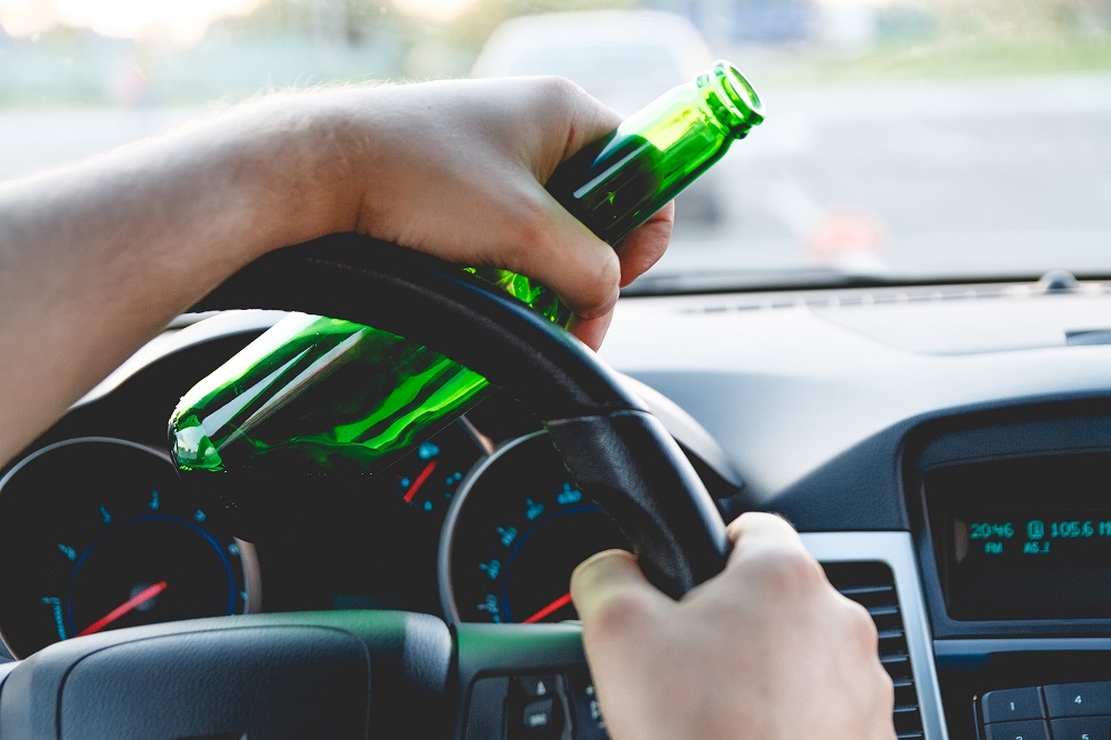 Man holding a bottle while driving